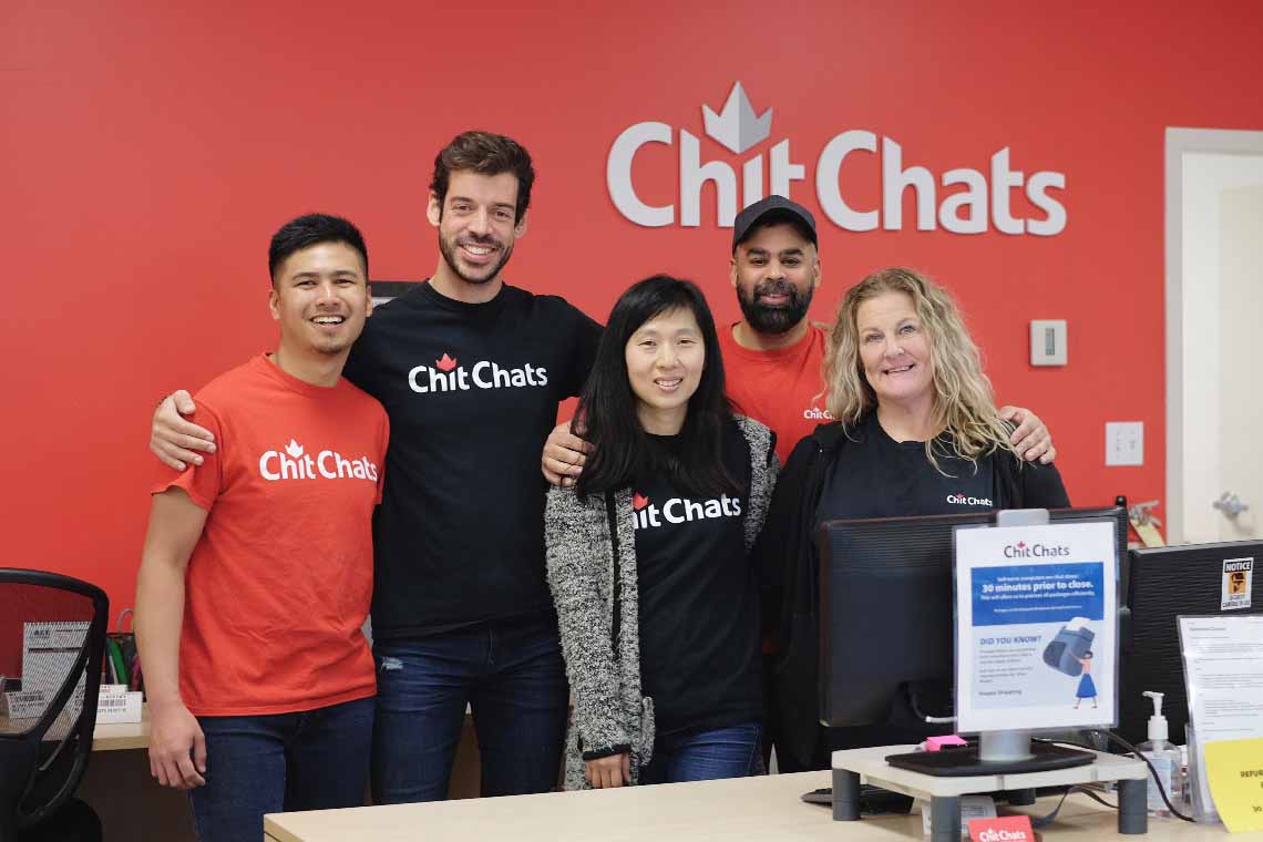 Five Chit Chats employees standing by a workstation in branch office